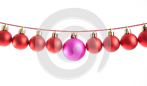 Line of red christmas balls and one lilac or purple ball on white background. Christmas decorations.