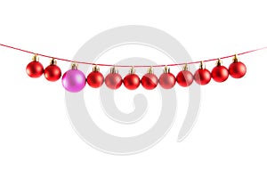 Line of red christmas balls and one lilac or purple ball on white background. Christmas decorations.