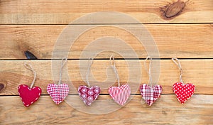 Line of red fabric hearts hanging, old wood background