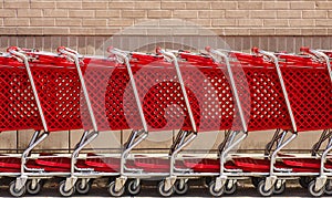 Line of Red Shopping Carts by Brick Wall