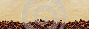 Line of roasted coffee beans on a brown craft paper background with copy space