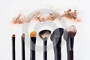 Line of scattered face powder and makeup brushes