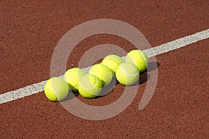 Line of seven yellow tennis balls on court