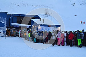 A line of skiers and snowboarders on the ski lift complex Big Woodyavr (Kirovsk, Russia)