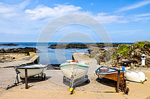 A line of three colorful old wood fishing boats pulled ashore at a small harbor