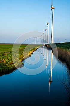 Line of windmills reflecting on a channel of water