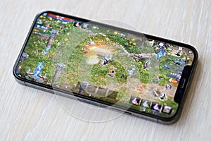 Lineage M mobile iOS game on iPhone 15 smartphone screen on wooden table during mobile gameplay