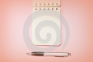 Lined notebook and pen on a pink background close-up. Top view, copy space. Education concept retro style toned