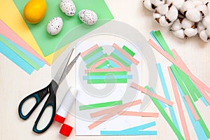 Lined strips of paper, multi-colored sheets, scissors, glue, Easter eggs on a light table. DIY concept. Step by step instructions