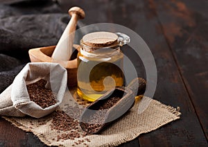 Linen bag of raw natural organic linseed flax-seed with spoon and oil on wooden background. Healthy omega 3 product