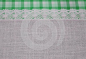 Linen cloth textile with lace lacy ribbon and border of green tartan pattern.