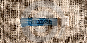 Linen fabric with a torn window in the middle with a Sexism sign in it