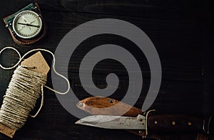 A linen rope, military compass and old hunting knife on the wooden table. photo
