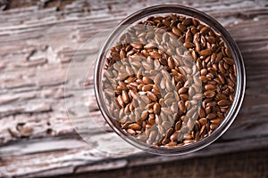 Linen seeds in a glass bowl on wooden stand closeup