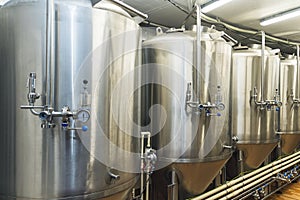 Lines of metal tanks in modern brewery. Shopfloor with brewery facilities. Manufacturable process of brewage. Mode of