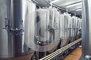 Lines of metal tanks in modern brewery. Shopfloor with brewery facilities. Manufacturable process of brewage. Mode of beer product