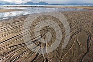 Lines in the sand on a beach of Alaska, with mountains in the background