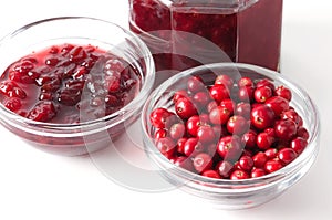 Lingonberries and lingonberry jam in glass bowls over white