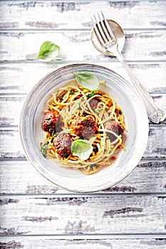 Linguine with meatballs, tomato sauce and basil leaves