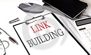 LINK BUILDING text on paper clipboard with chart and notebook on withe background