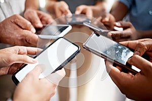 Link up with like minded go getters. Shot of a group of unrecognisable businesspeople using their smartphones in a