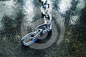 Links of a metal chain on a dark floor background. Selective focus. Close-up