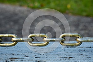 Links of taut steel chain over wood