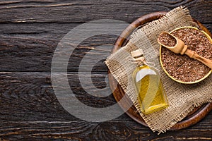 Linseed oil and bottle of linseeds on wooden background.