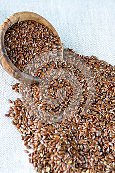Linum usitatissimum flax seeds scattered around a plate of olive wood. Useful and medicinal product.