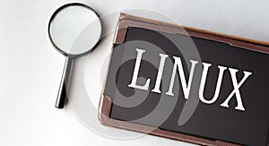 LINUX - word in electronic notebook on white background with magnifying glass photo