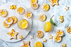 Linzer Christmas cookies filled with lemon curd and dusted with sugar on white marble board.