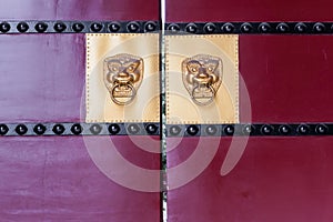 Lion door knockers on a red gate