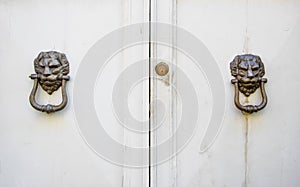 Lion head knockers on an old white wooden door