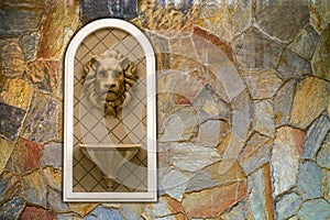 Lion head statue on cavernous stone wall. concept decoration architecture sculpture low relief ornament. photo