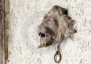 Lion`s Head with Door Knocker below, on a wall in Gruyeres