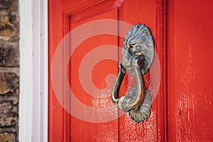 Lion`s head door knocker on a red door on a British house.