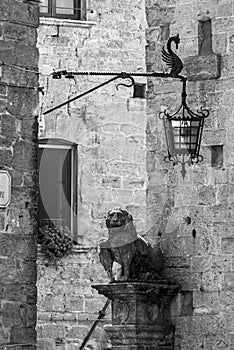 A lion statue and an old vintage street light in the city of Volterra