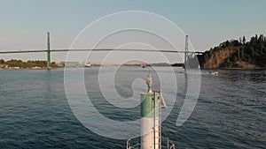 Lions Gate Bridge in Vancouver's harbor with pleasure craft passing by next to Stanley Park. 4K 24FPS.