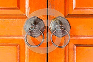 Lions` handles hang on a traditional Chinese door.