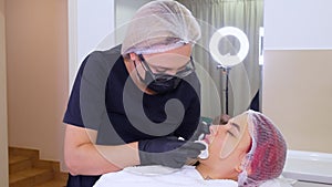 Lip augmentation procedure. Surgeon, in medical gloves, kneads and massages female lips to evenly distribute hyaluronic