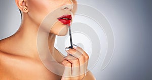 Lip brush, makeup and person in studio, red lipstick and beauty for cosmetics, glow and shine of aesthetic. Self love