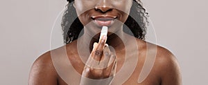 Lip Care. African Female Using Chapstick To Moisturise Her Beautiful Plump Lips photo