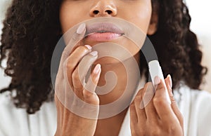 Lip Care. Unrecognizable black woman applying moisturising chapstick on lips, closeup