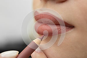 Lip makeup. Close-up of a cosmetologist painting her lips with a pencil before permanent makeup.