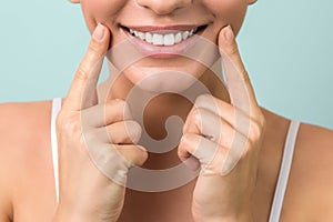 Lip protection. close up of a young woman beautiful smile, healthy lips and white teeth on aqua-mint background