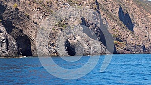 Lipari Island, mountain with caves in Mediterranean sea. Summer sunny day, blue sky. Rippling blue water surface. Sicily