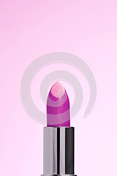 Lipctick bullet macro.  Close up of lipstick in silver packaging on pink background