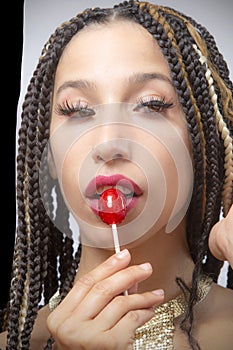 Lips of beautiful young Latina touching a red candy pop