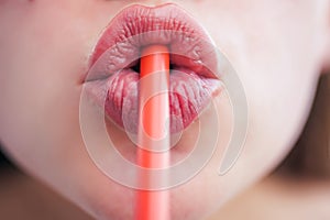 Lips close up drinking through straw. Female mouth drinking. Drinking tube is a small pipe to consume a beverage.