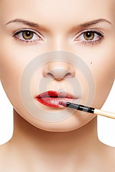 Lips make-up. Applyng red lipstick using lip brush